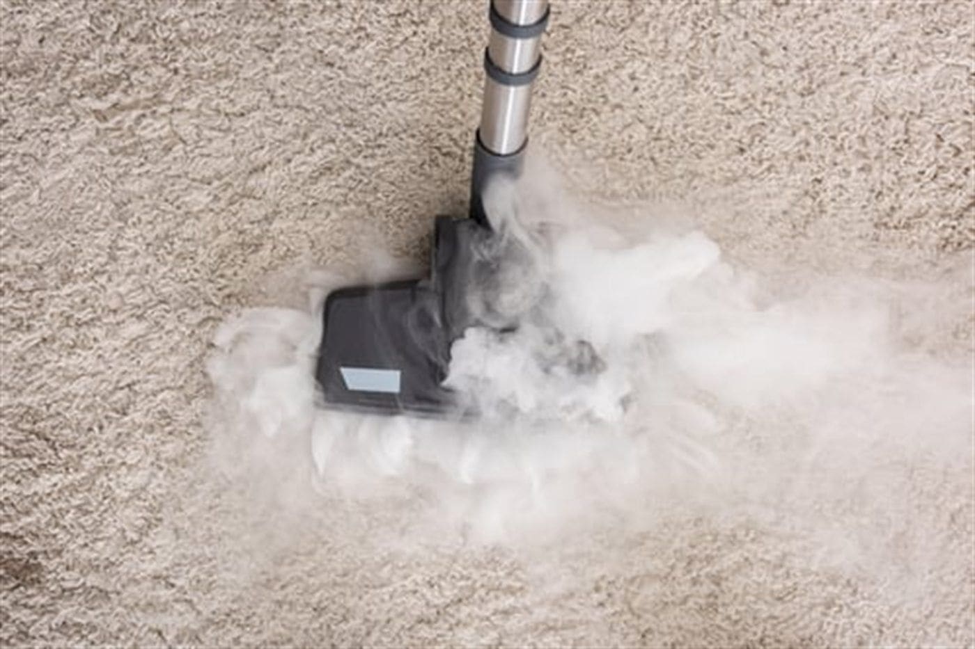 Hot-water extraction machine steam cleaning a light-coloured living room carpet
