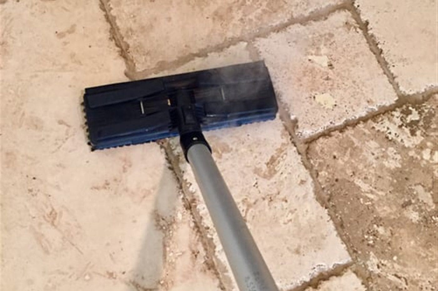 Close-up of tile floor and grout lines being deep cleaned with a professional cleaning head